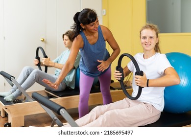 Young boy and girl doing pilates exercises during group training. Hispanic woman trainer teaching them.