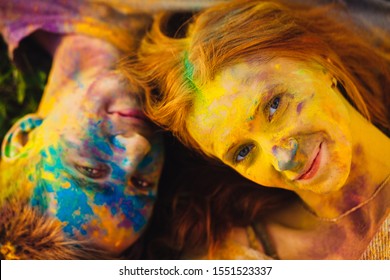 Young boy and girl in Holi colors. An attractive guy and girl are lying on the grass in a beautiful summer park. 