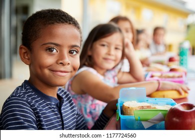Young boy   girl at school lunch table smiling to camera