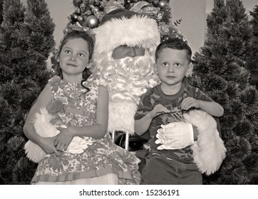 Young Boy And Girl Sitting On Santa Claus' Lap