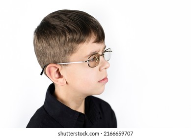 A Young Boy In Glasses To Improve Eyesight, He Has Gadgets, Games On The Phone, His Eyesight Has Deteriorated And Now He Is Forced To Temporarily Wear Glasses, Side View. Eye Health Concept