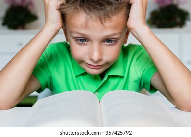 Young Boy In Green Polo Shirt Having Serious Learning Difficulties While Trying To Read A Textbook From School.