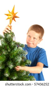 Young boy grimacing while decorating Christmas tree, studio shot with copy space