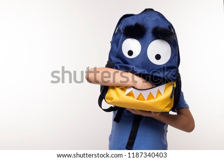 Young boy with hand inside his school bag pocket, monster face backpack, halloween or back to school during Covid19 pandemic