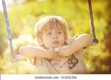 Young Boy Hanging On A Bar On A Swingset