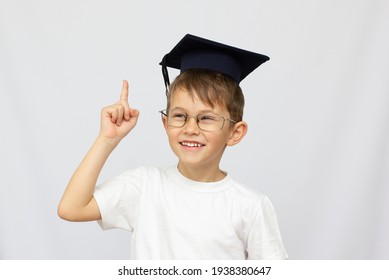A young boy has a graduation black cap with a tassel on a white isolated background. Use it for a school or education concept.