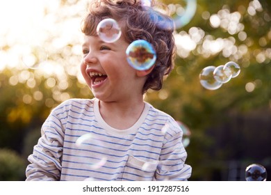 Young Boy Having Fun In Garden Chasing And Bursting Bubbles - Powered by Shutterstock