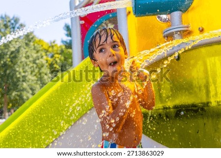 Young boy is having fun playing under refreshing water jets at a colorful water park in kamloops, british columbia, experiencing the joy of summer