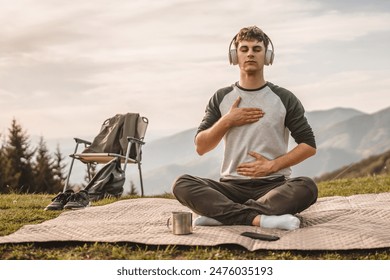 Young boy with headphones, meditate and sit down in front of tent on the mountain - Powered by Shutterstock