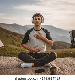 Young boy with headphones, meditate and sit down in front of tent on the mountain - Powered by Shutterstock