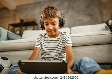 young boy with headphones sit on the floor and use digital tablet - Powered by Shutterstock