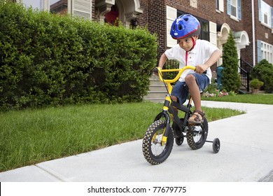 Young Boy With Helmet Riding His First Bicycle With Training Wheels