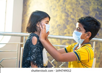 Young Boy Helping His Sister To Adjust Her Protective Mask On Face. Kids In Isolation, Quarantine, Stay At Home, Due To New Strain Of Covid-19 , Children Getting Infected Due To Omicron Cases In India