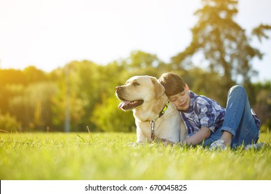 Young boy and his dog lying on the grass together. Happy boy hugging his pet Labrador smiling with his eyes closed copyspace nature happiness support friendship peaceful summer animals lifestyle