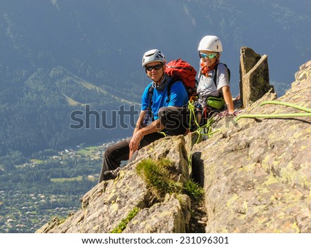 Young boy and his father at a belay station whilst rock climbing in the Aiguille Rouge national park in the alps high above Chamonix.