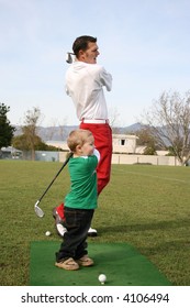 Young boy and his father practicing on the driving range. Focus set on child.