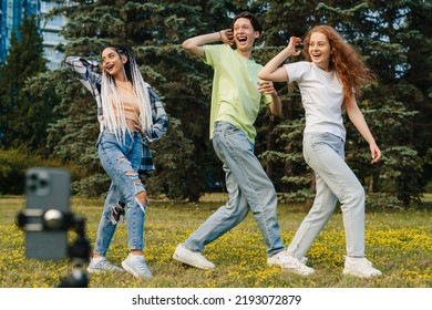 Young boy with his friends dancing recording video by smartphone camera. Enjoying free time in the city park. Popular bloggers. - Powered by Shutterstock