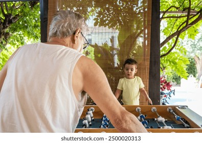 Young boy and his grandfather enjoying a multigenerational foosball game. - Powered by Shutterstock