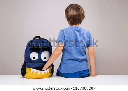 Young boy with his hand inside backpack pocket, education during covid19 pandemic Funny cute monster face backpack