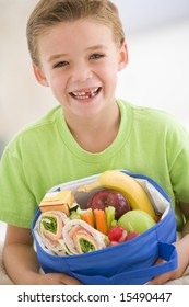 Young Boy Holding Packed Lunch In Living Room Smiling