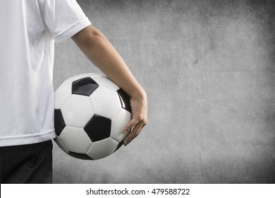Young boy holding a soccer ball in front of a uniform grey background. Space left for text.