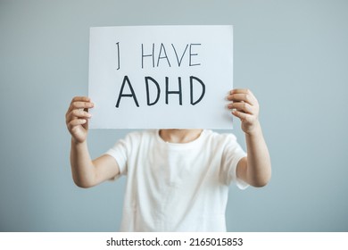 Young boy holds ADHD text written on sheet of paper. ADHD is Attention deficit hyperactivity disorder. Close up.. Attention Deficit Hyperactivity Disorder or ADHD