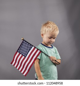 A young boy holds an American flag over his shoulder.