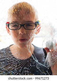 A Young Boy Holds A Golf Ball, Which He Just Used To Accidentally Break A Window.