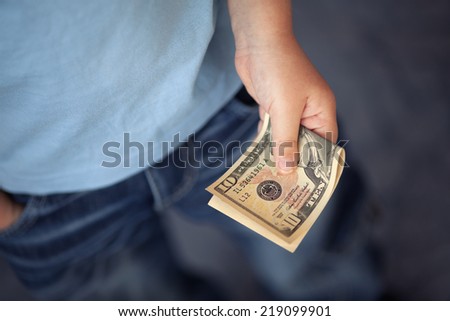 Young boy holds ten dollars.