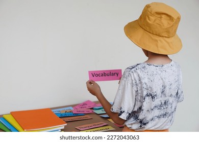 Young boy holds word card to practice English vocabulary. Concept, learning vocabulary. Language study. Education. Reading and memorizing strategy of learning process for kid. Practice makes perfect. - Shutterstock ID 2272043063