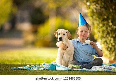 Young Boy Hugging His Dog While Eating An Ice Block At A Birthday Party.