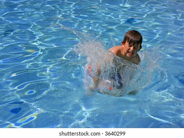 A Young Boy Jumping And Splashing Into A Swimming Pool. Cannonball!