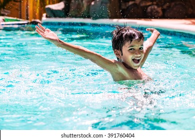 Young boy kid child eight years old splashing in swimming pool having fun leisure activity open arms - Powered by Shutterstock