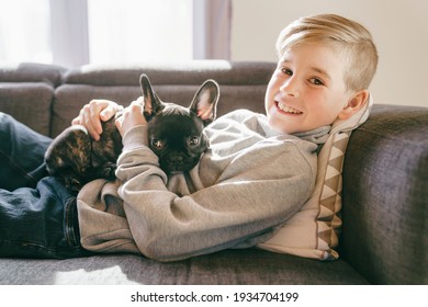 A Young Boy Laughing With French Bulldog Puppy On His Lap