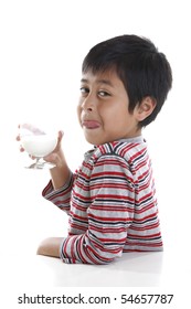 A Young Boy Licking His Lips While Drinking A Glass Of Milk