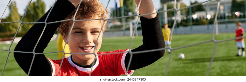 A young boy with a look of determination stands behind a soccer net. He is practicing his goalkeeping skills, ready to defend the goal with agility and precision. - Powered by Shutterstock