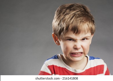 Young Boy Looking Angry, Clenching Teeth Against Gray Background