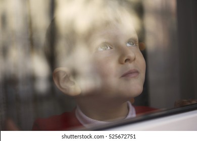 Young Boy Looking Outside Through A Window