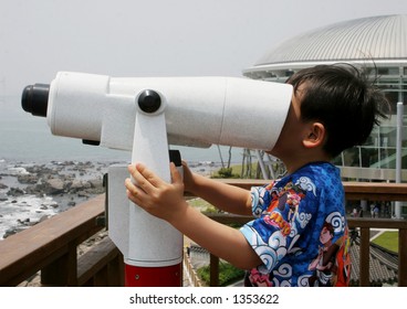 Young Boy Looking In A Telescope At The Sea The Wrong Way