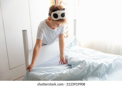 Young Boy Making His Bed In The Morning In Sunny Bedroom.