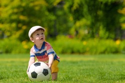 Young Boy On A Green Field In The Park With A Football