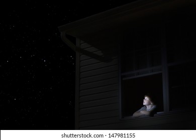 Young Boy At Open Window Looking At Night Sky