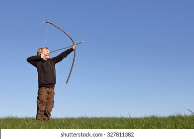 Young Boy Outdoors With Bow And Arrow