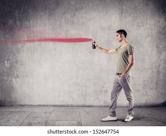 Young Boy Painting On The Wall With Red Spray