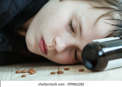 Young boy passed out on drugs and alcohol or dead after committing suicide lying on the floor with an empty medication bottle at his head and capsules around his face