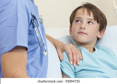 Young Boy Patient In A Hospital Bed Being Reassured By A Female Doctor With Stethoscope