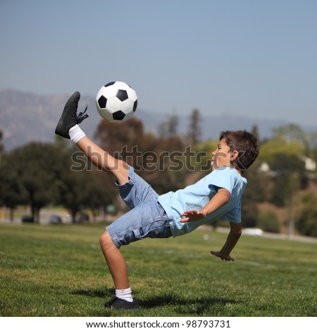 A young boy performs a soccer 