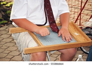 Young Boy Playing An Antique Washboard With A Coin