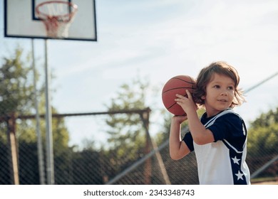 Young boy playing basketball on a basketball court outside - Powered by Shutterstock