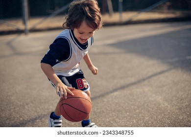 Young boy playing basketball on a basketball court outside - Powered by Shutterstock